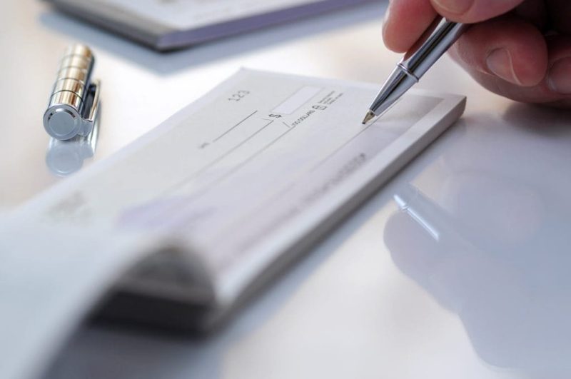 Close-up businessman hand hold pen fill a banque cheque document